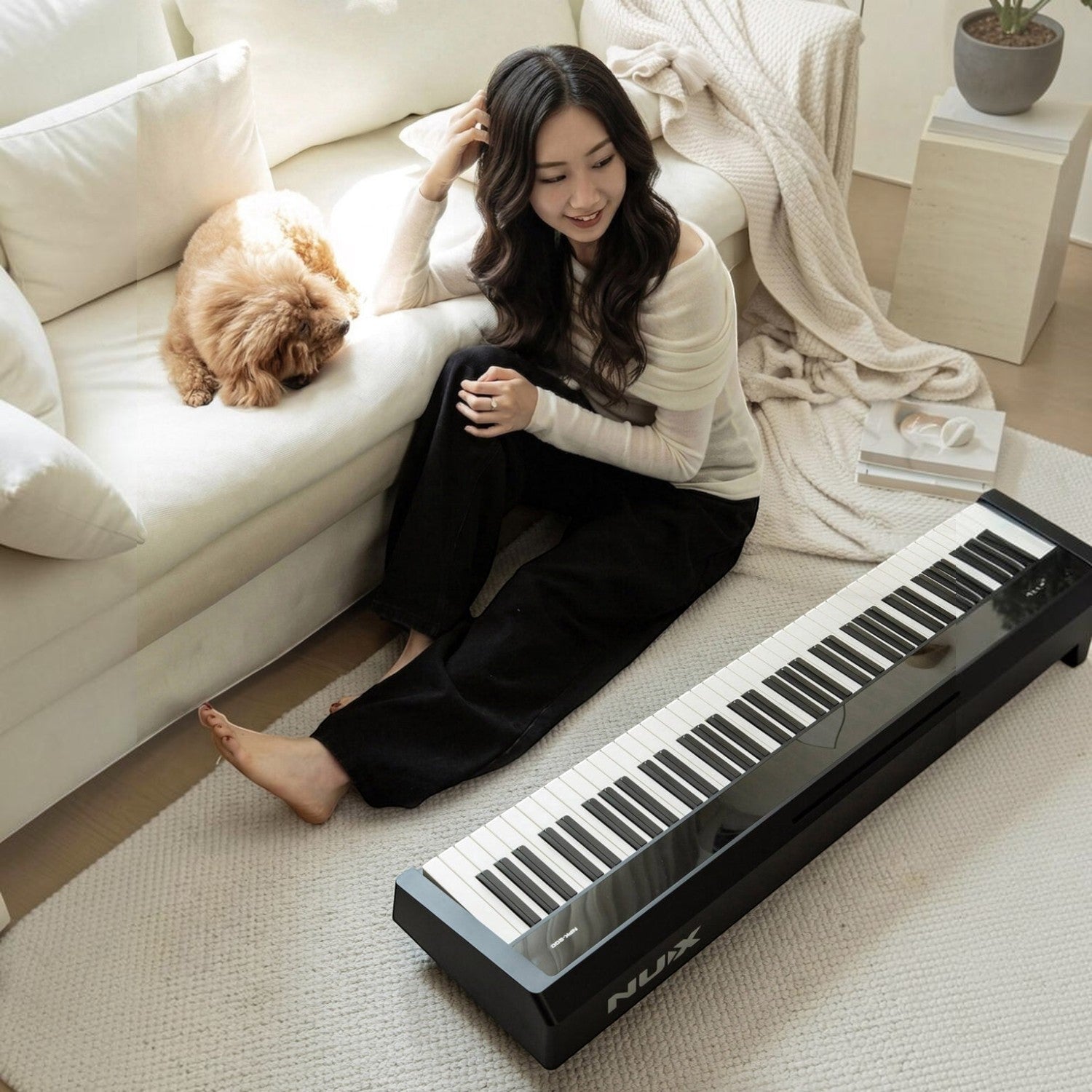 Cô gái trẻ ngồi trên thảm bên cạnh đàn piano điện TÂN NHẠC CỤ Nux NPK200 màu đen trong không gian phòng khách ấm cúng