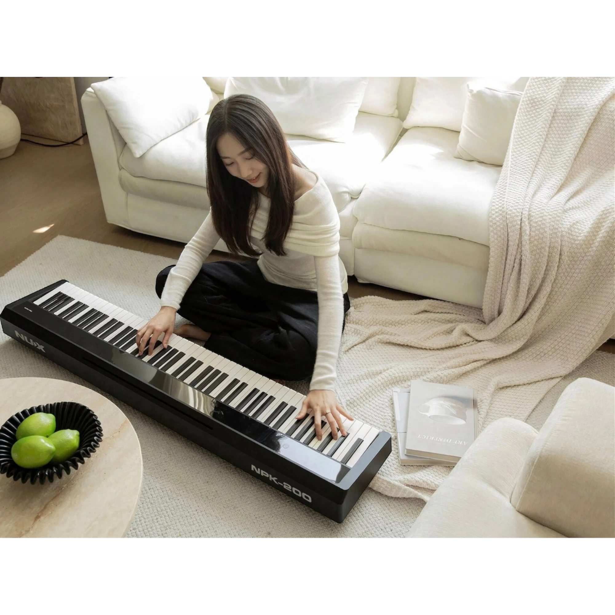Cô gái trẻ chơi đàn piano điện Nux NPK200 màu đen tại Tân Nhạc Cụ, thiết kế hiện đại trong không gian phòng khách.