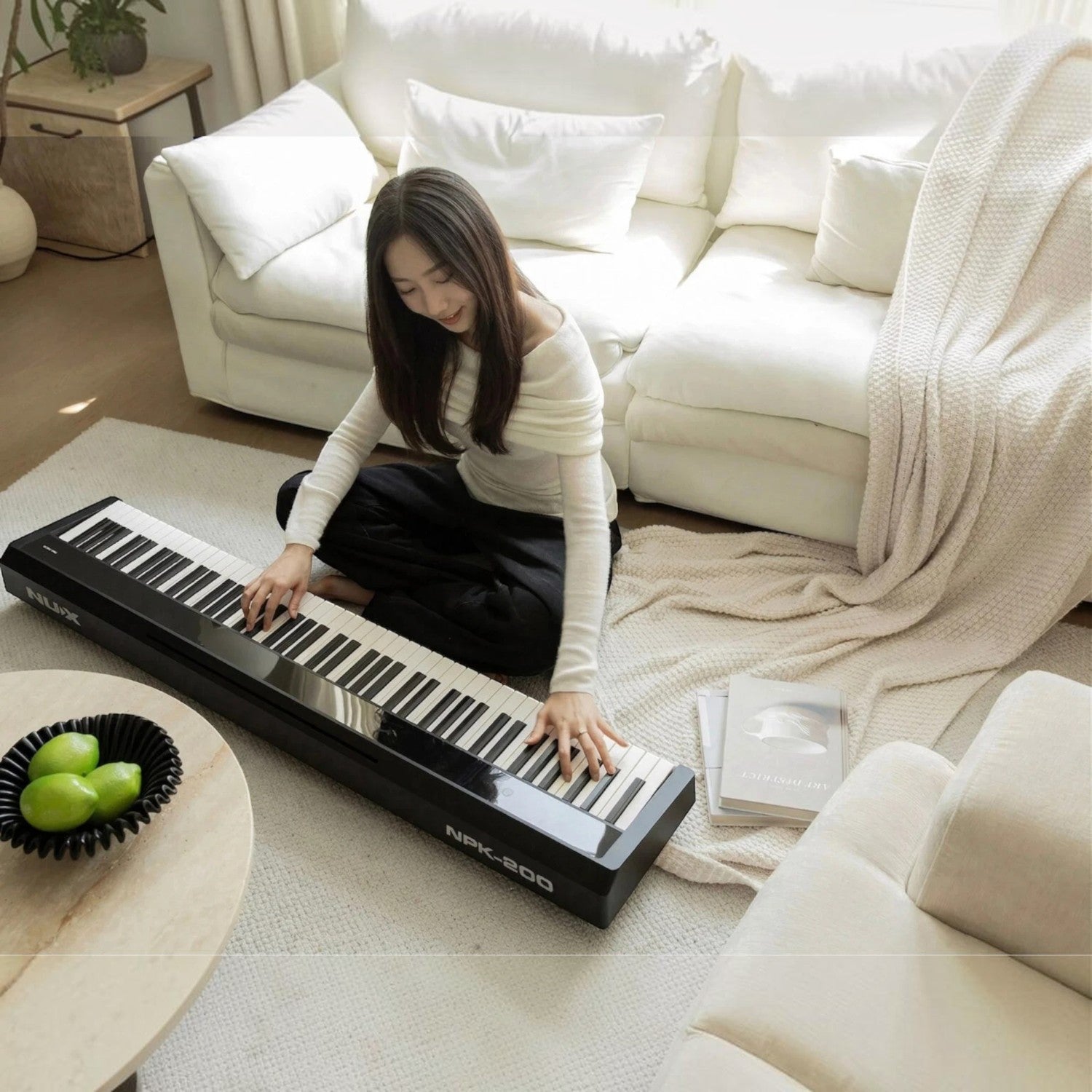 Cô gái trẻ chơi đàn piano điện Nux NPK200 màu đen hiện đại trong không gian phòng khách ấm cúng tại TÂN NHẠC CỤ