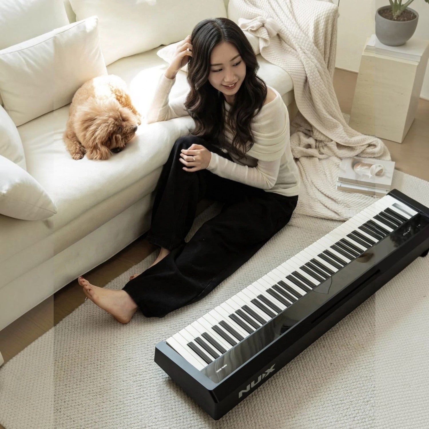 Cô gái trẻ ngồi cạnh đàn piano điện Nux NPK200 màu đen trong không gian phòng khách ấm cúng tại TÂN NHẠC CỤ