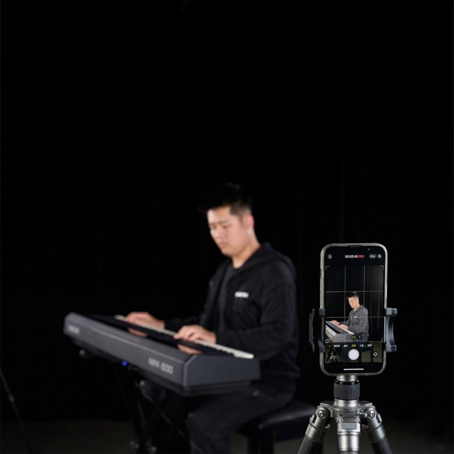 Nam nhạc sĩ đang chơi đàn piano điện Nux NPK200 của TÂN NHẠC CỤ, được quay lại bằng điện thoại trên chân máy