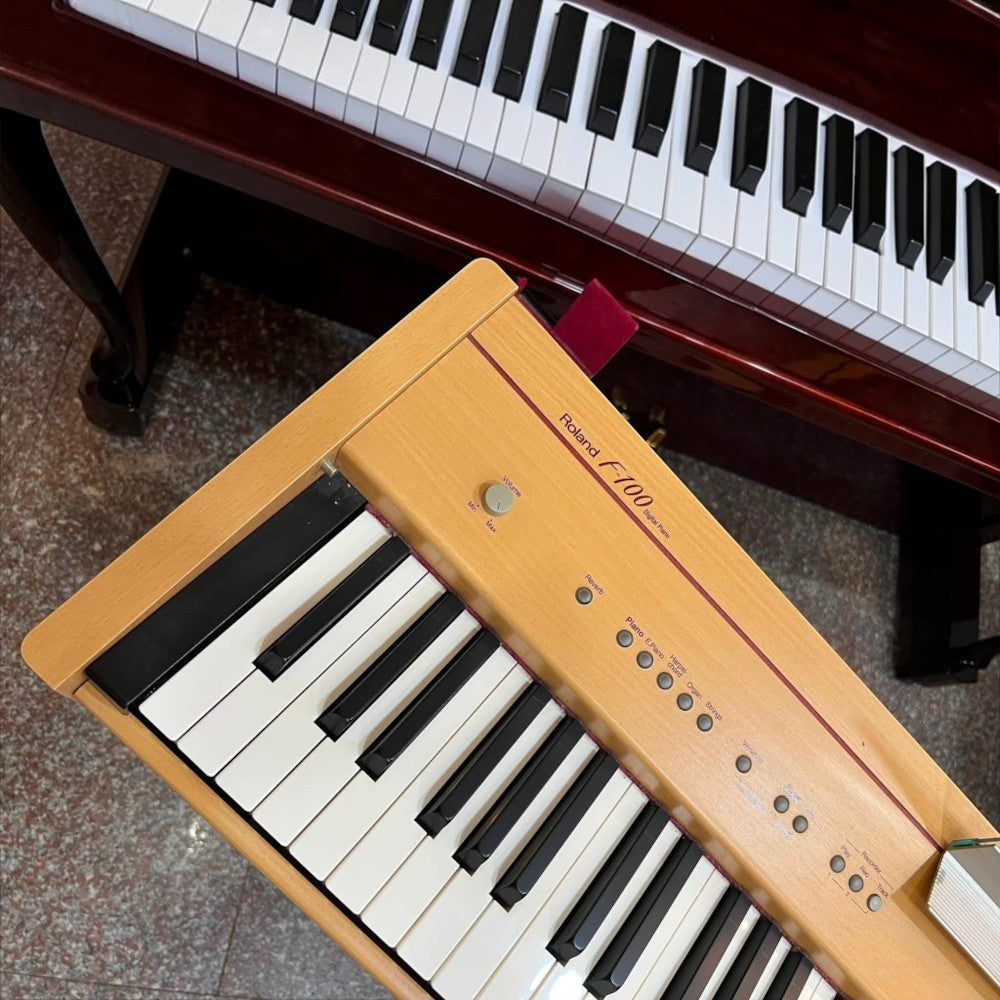 Đàn piano điện Roland F100 màu gỗ thích tại TÂN NHẠC CỤ với bàn phím búa 88 phím và thiết kế tủ gọn gàng
