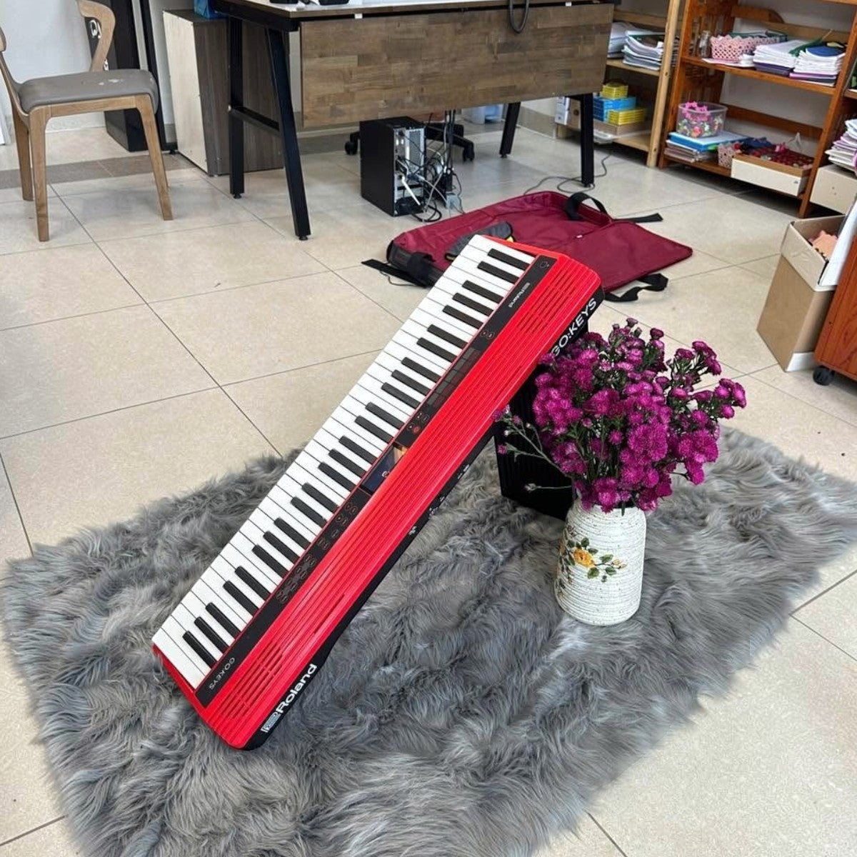 Đàn piano điện Roland GO:61 màu đỏ nổi bật, thiết kế nhỏ gọn đặt trên thảm lông xám tại showroom Tân Nhạc Cụ