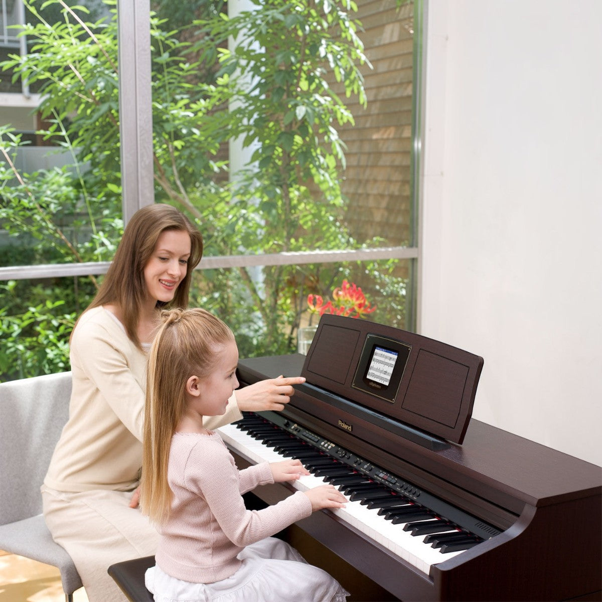 Mẹ và bé đang học đàn piano điện Roland HPi6S tại TÂN NHẠC CỤ với màn hình DigiScore hiển thị nốt nhạc trực quan