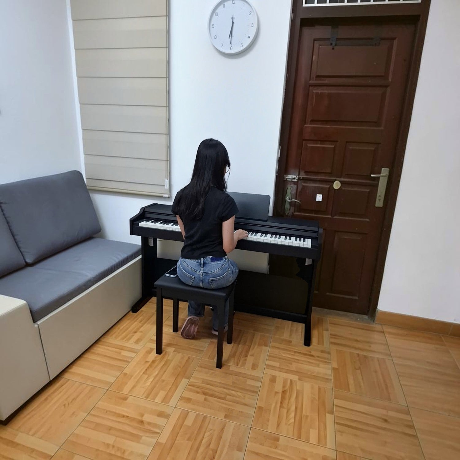 Cô gái đang chơi đàn piano điện Roland RP107 màu đen trong phòng khách tại Tân Nhạc Cụ