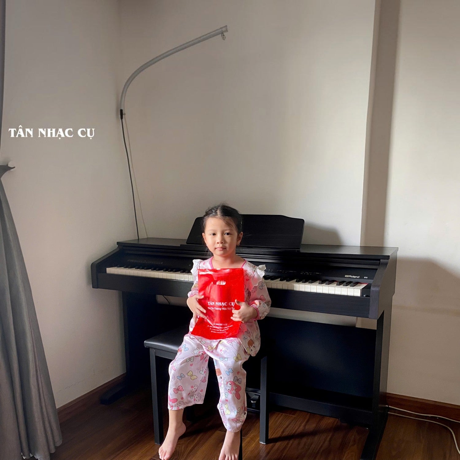 Bé gái ngồi chơi đàn piano điện Roland RP30 màu gỗ hồng sẫm tại showroom TÂN NHẠC CỤ