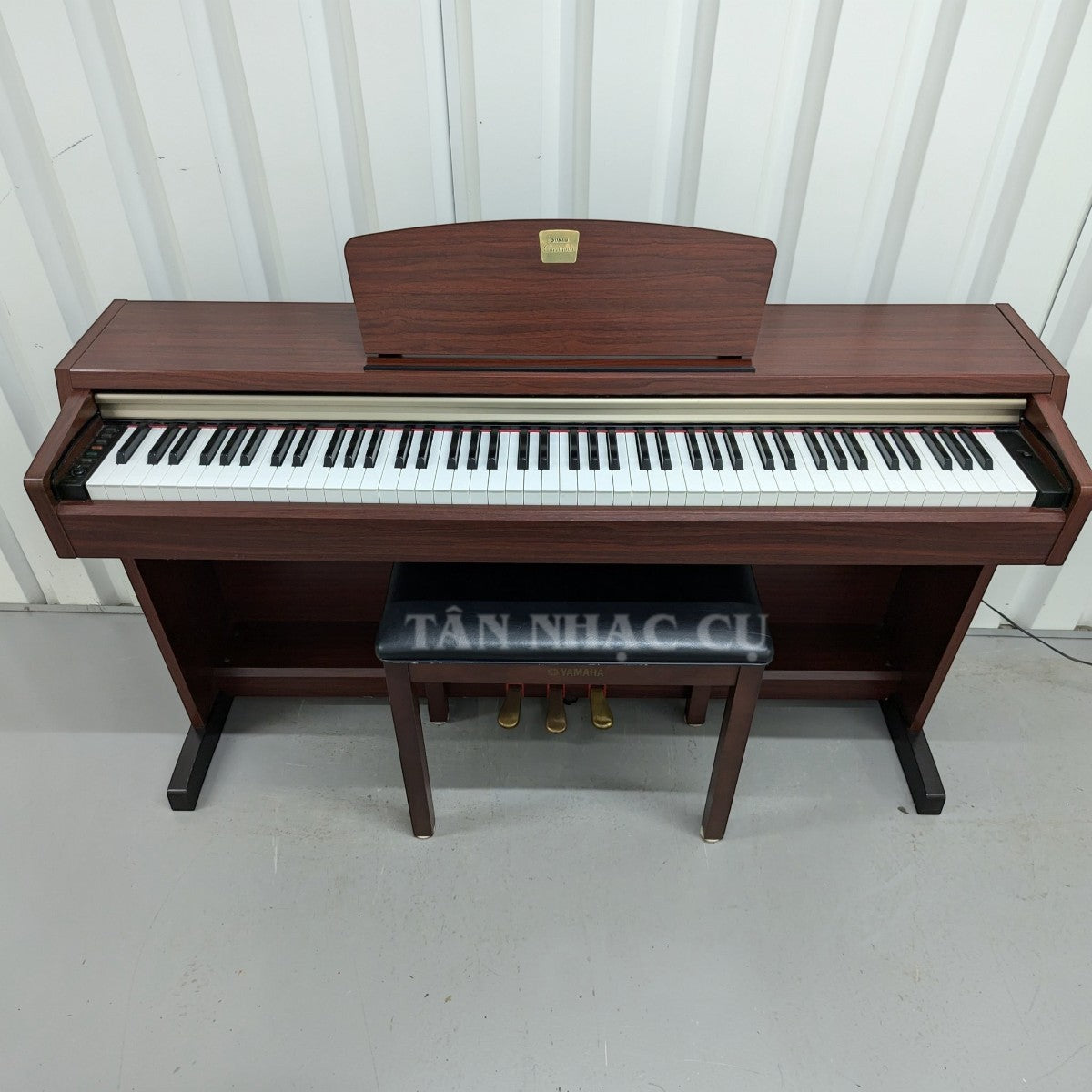 Đàn piano điện Yamaha CLP220 dáng tủ màu gỗ tại TÂN NHẠC CỤ, thiết kế upright thanh lịch với 3 pedal và ghế đàn