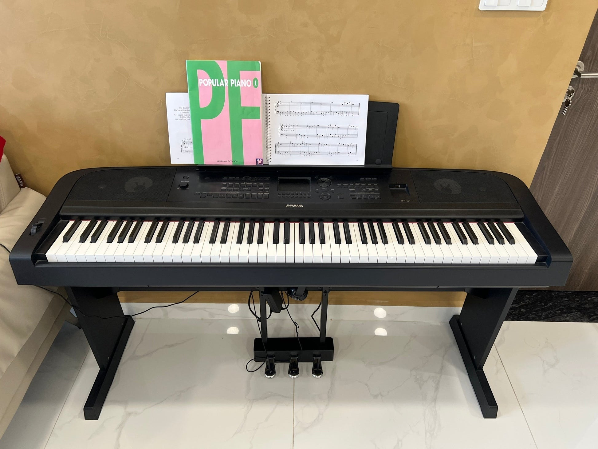 Đàn piano điện TÂN NHẠC CỤ Yamaha DGX670 màu đen với 88 phím GHS và giá để bản nhạc trong không gian nội thất