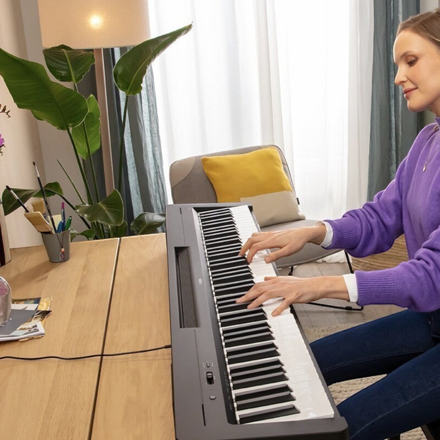 Người phụ nữ chơi đàn piano điện Yamaha P-145BT màu đen trong không gian phòng khách hiện đại tại Tân Nhạc Cụ