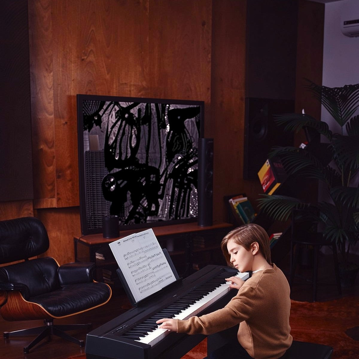 Cậu bé chơi đàn piano điện Yamaha P45 cũ màu đen tại Tân Nhạc Cụ, thiết kế 88 phím GHS trong không gian phòng khách