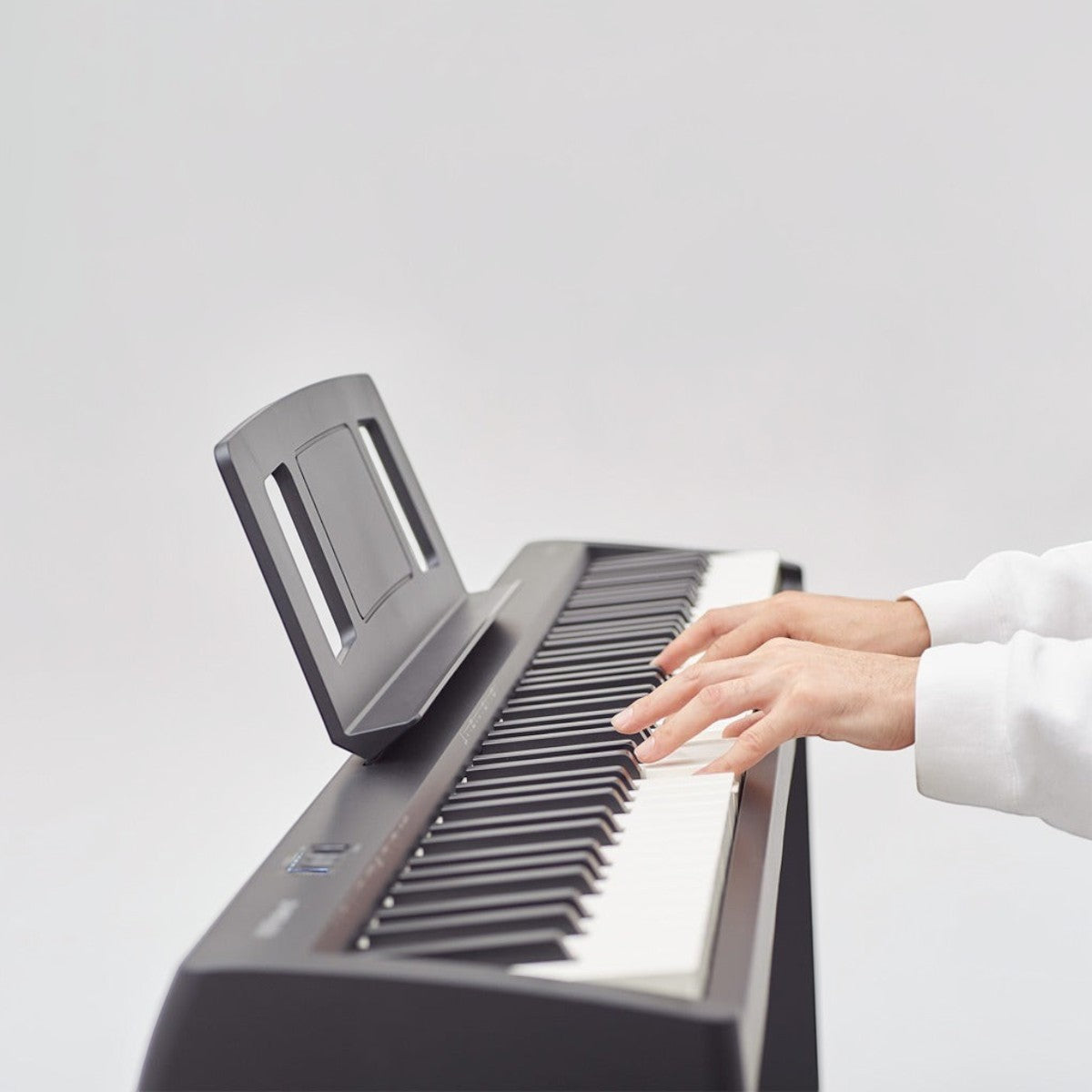 Người chơi đang thử bàn phím đàn piano điện Yamaha P-45 màu đen tại TÂN NHẠC CỤ