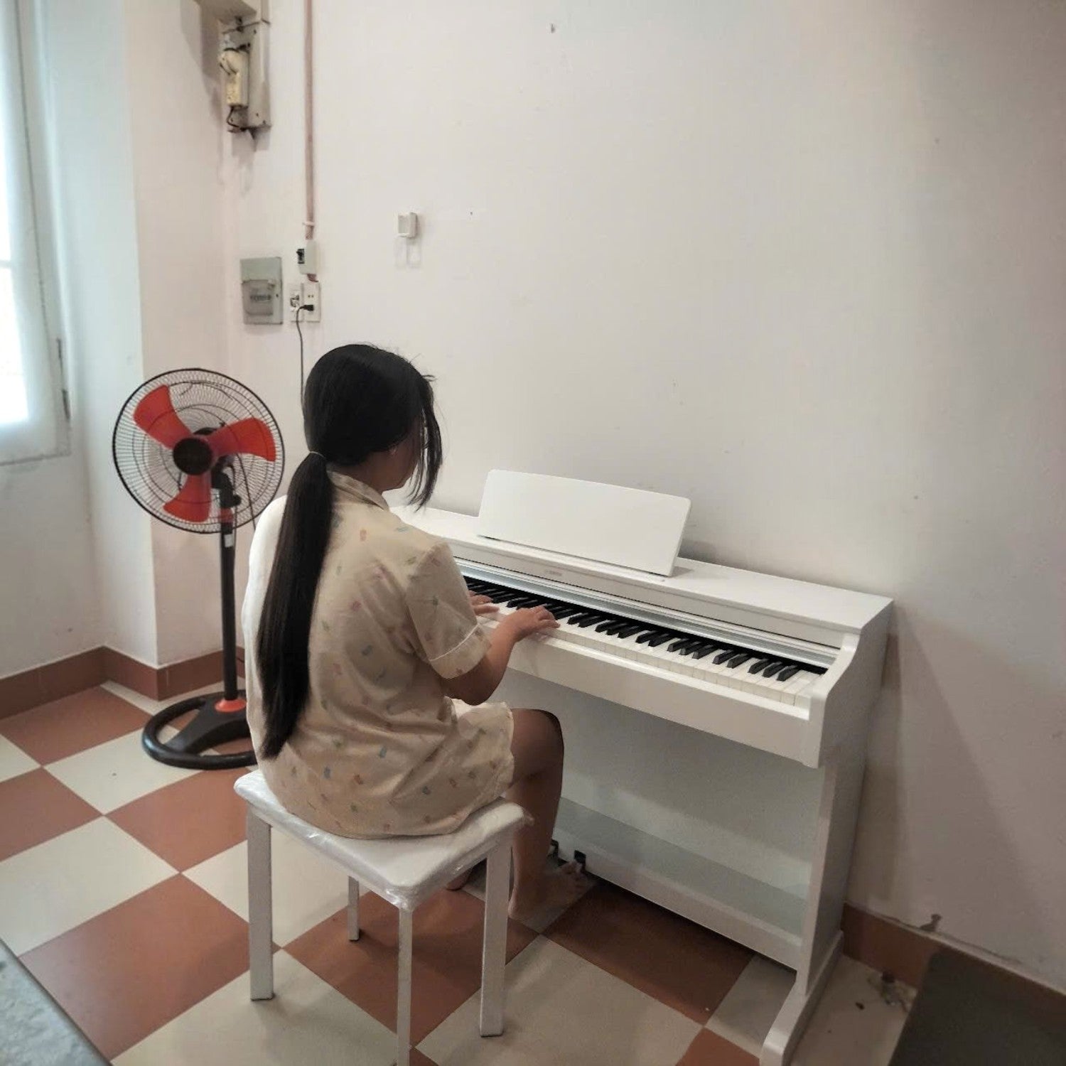 Cô gái đang chơi đàn piano điện Yamaha YDP-163 màu trắng tại Tân Nhạc Cụ, thiết kế dáng tủ hiện đại và thanh lịch.