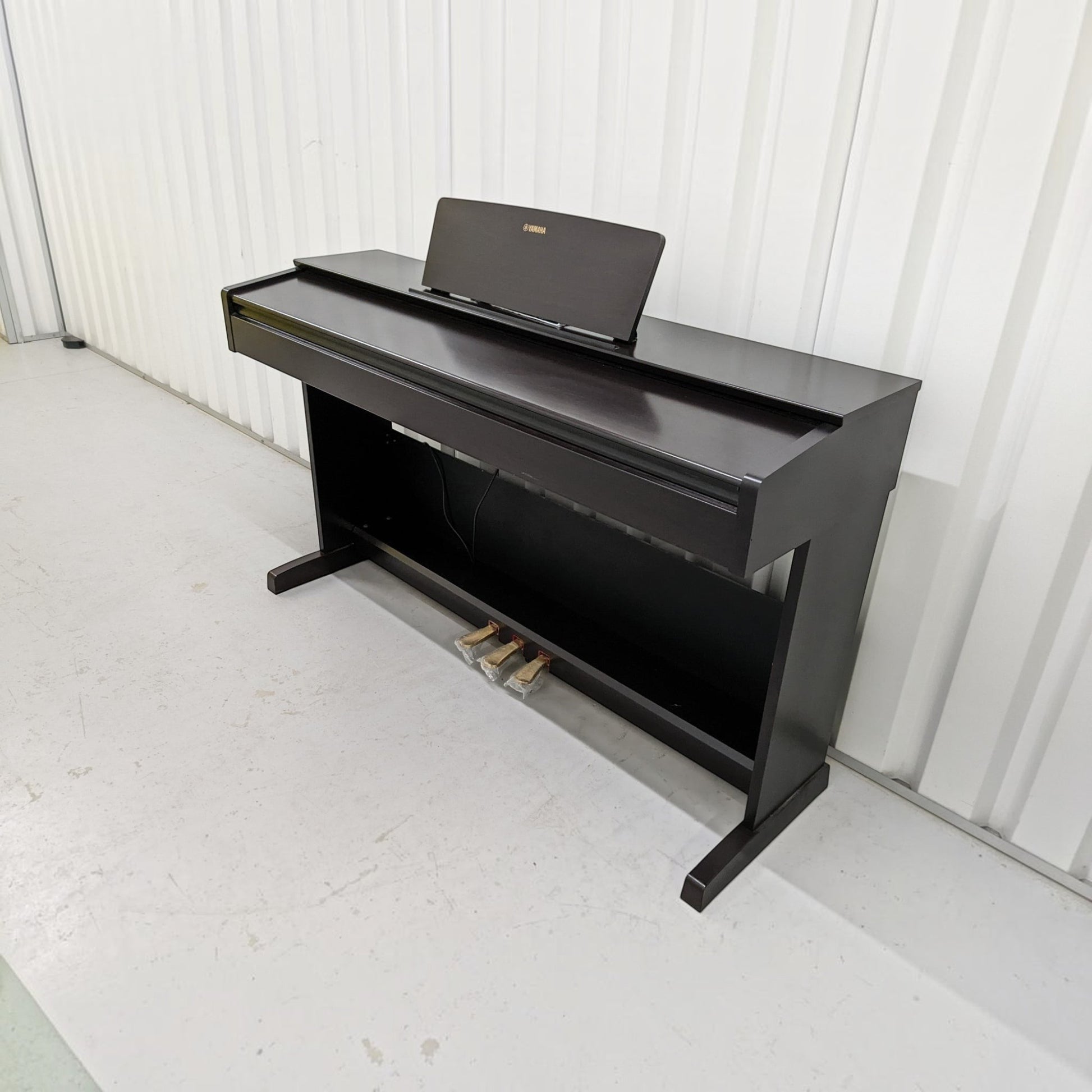 Đàn piano điện Yamaha YDP-103 màu đen dáng tủ tại TÂN NHẠC CỤ, thiết kế gọn gàng với 3 pedal và giá để nhạc.
