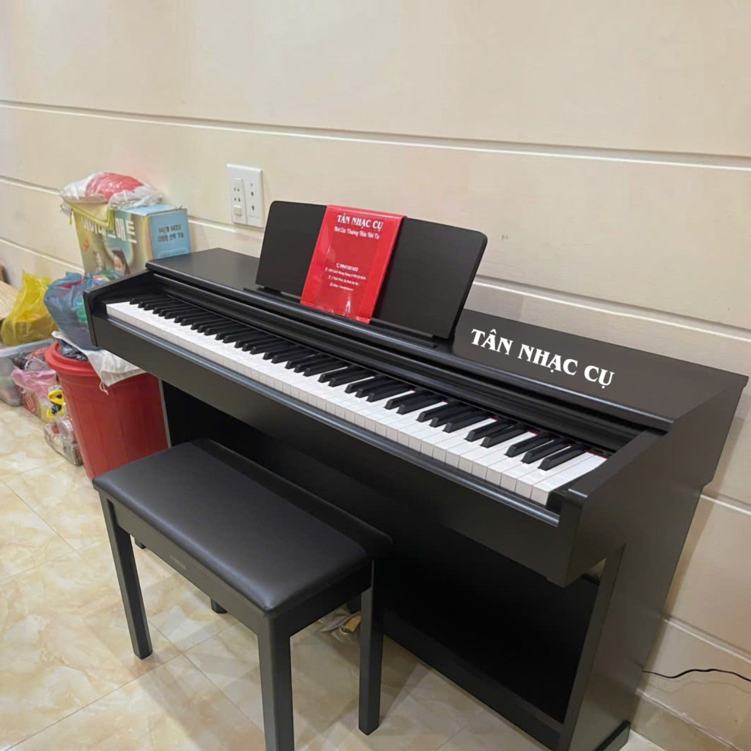 Đàn piano điện Yamaha YDP-105 màu đen tại TÂN NHẠC CỤ, thiết kế dáng tủ đứng với 88 phím búa và ghế đi kèm.