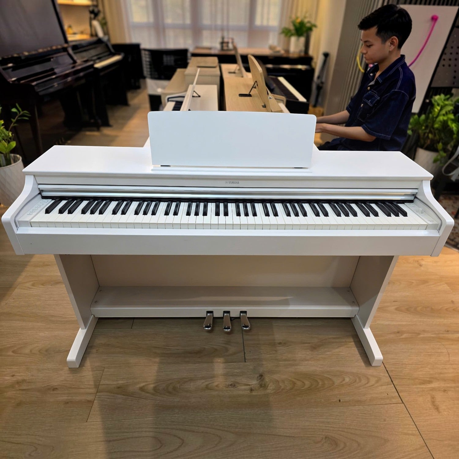 Đàn piano điện Yamaha YDP-163 màu trắng tại showroom TÂN NHẠC CỤ, có người đang chơi thử đàn.