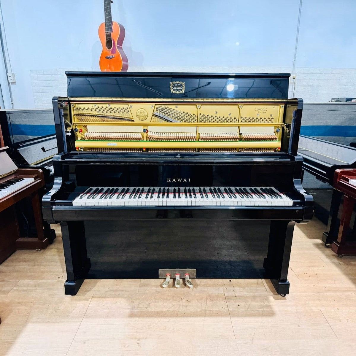 Đàn piano cơ upright Kawai US7X màu đen bóng tại Tân Nhạc Cụ với bộ máy bên trong lộ rõ và phím ngà nhân tạo