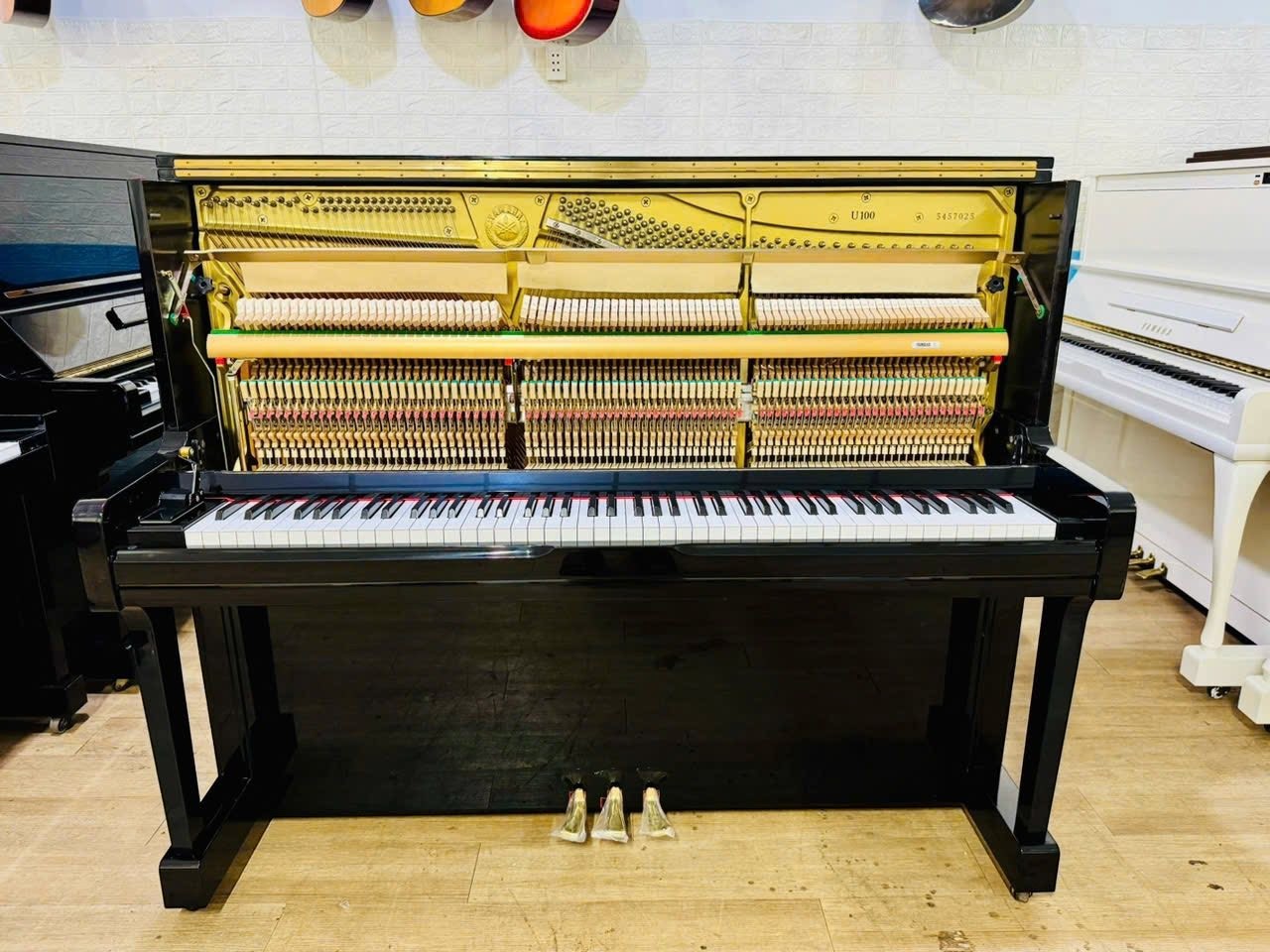Đàn piano cơ TÂN NHẠC CỤ Yamaha U100 màu đen bóng với bộ máy bên trong lộ rõ, thiết kế hiện đại, sang trọng.