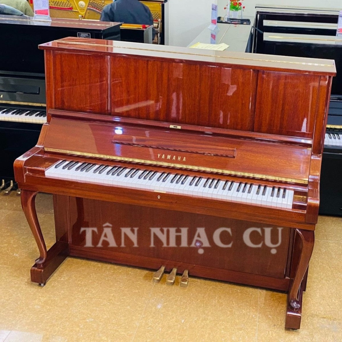 Đàn piano cơ Yamaha W106B tại TÂN NHẠC CỤ với mặt vân gỗ óc chó và gụ cổ điển, thiết kế sang trọng, âm thanh ấm áp.