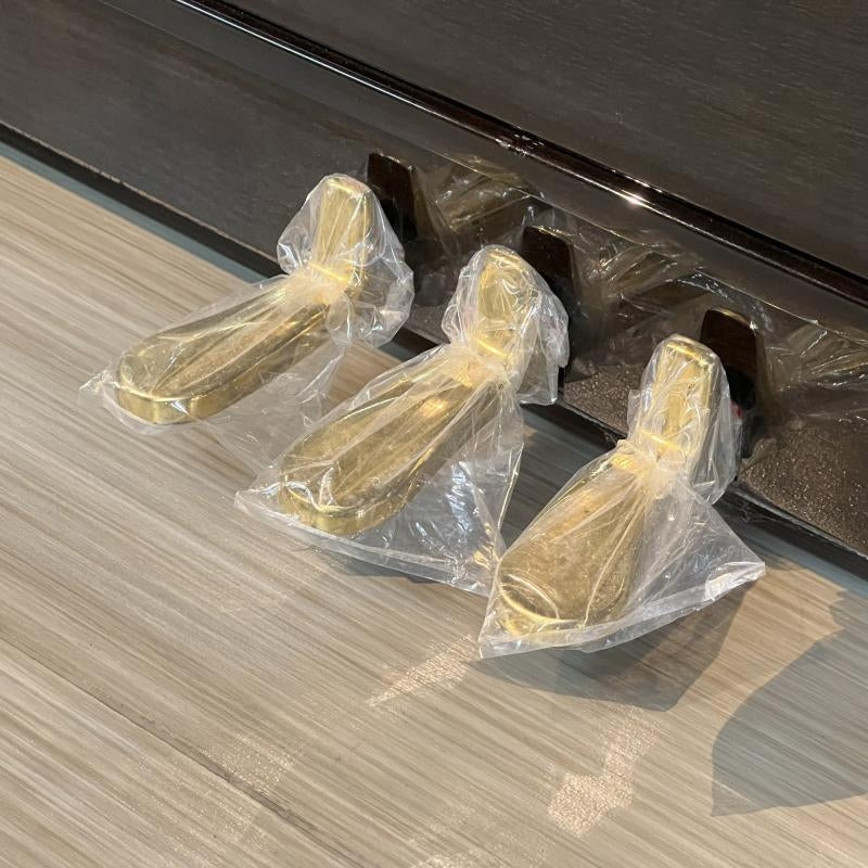 Bộ ba bàn đạp pedal bằng đồng sáng bóng của đàn piano cơ Diapason D66W tại TÂN NHẠC CỤ, được bọc bảo vệ cẩn thận.