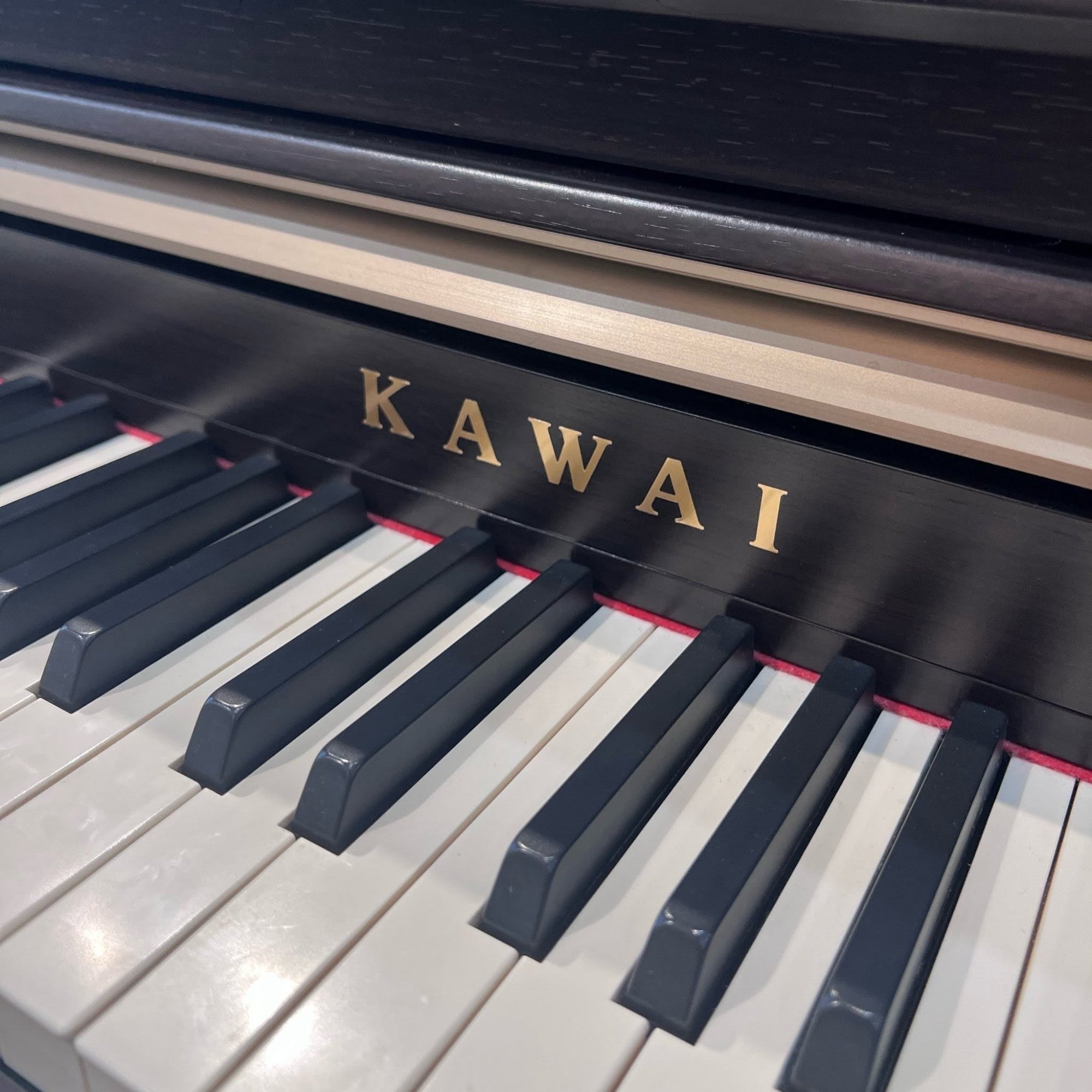 Cận cảnh bàn phím gỗ Grand Feel và logo Kawai trên đàn piano điện Kawai CA65 qua sử dụng tại Tân Nhạc Cụ