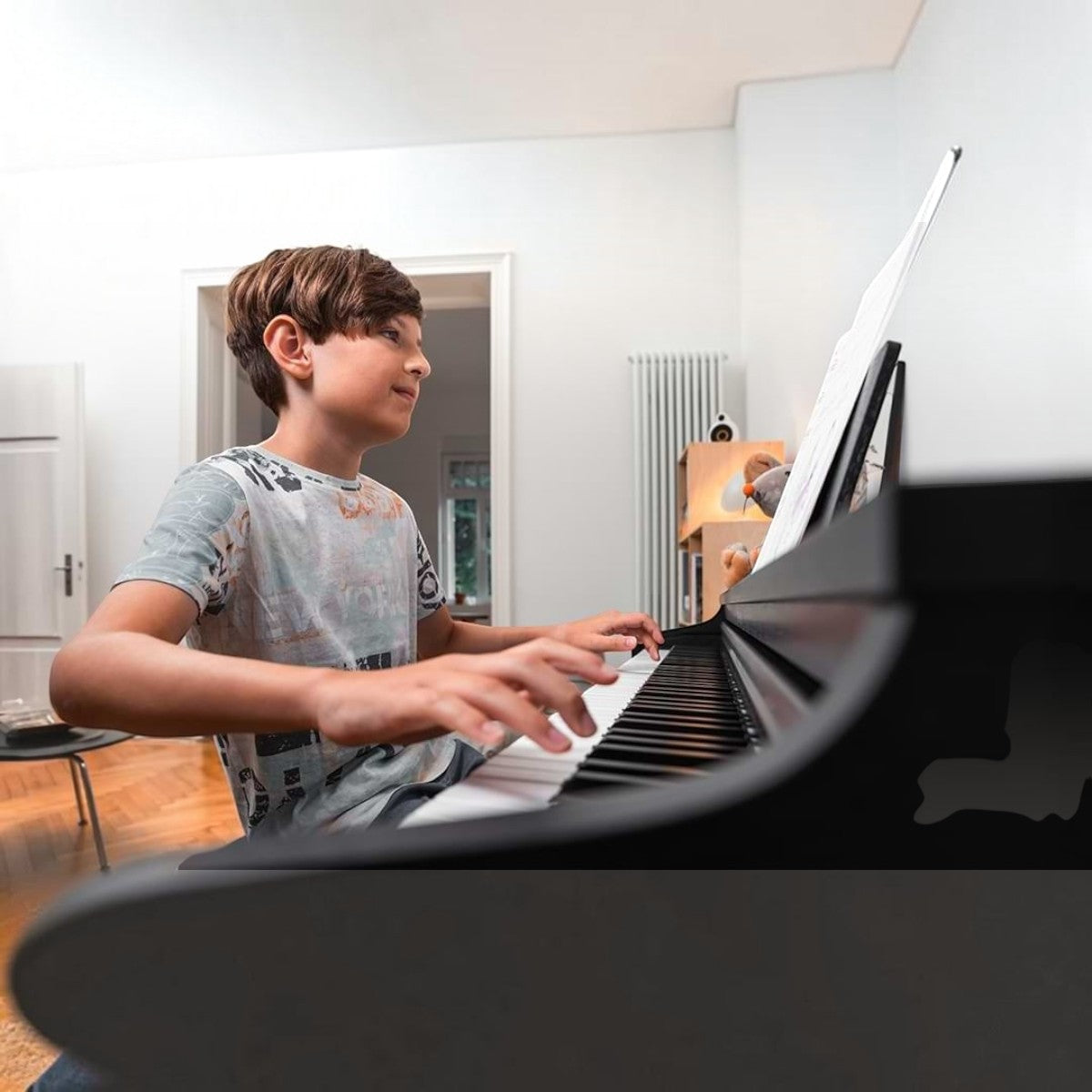 Cậu bé đang chơi đàn piano điện Kawai CX202 màu đen tại Tân Nhạc Cụ, tập trung với bàn phím búa Responsive Hammer Compact II