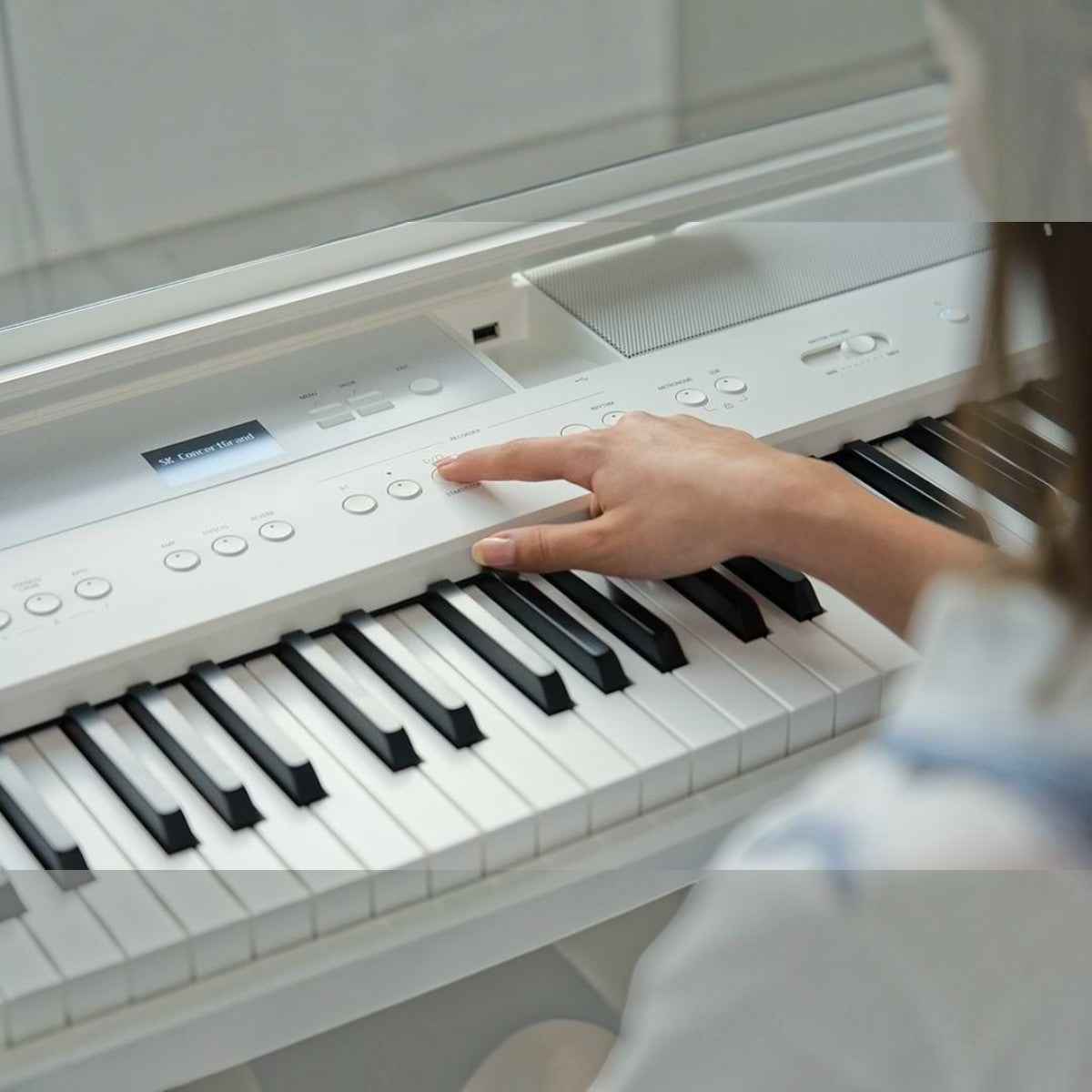 Người chơi đang thao tác trên bảng điều khiển màn hình OLED của đàn piano điện Kawai ES520 màu trắng tại Tân Nhạc Cụ