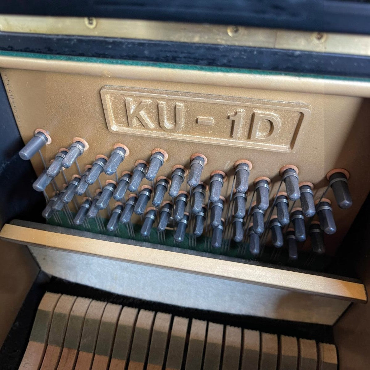 Khung gang bên trong đàn piano cơ TÂN NHẠC CỤ Kawai KU1D với các chốt lên dây và ký hiệu model rõ nét