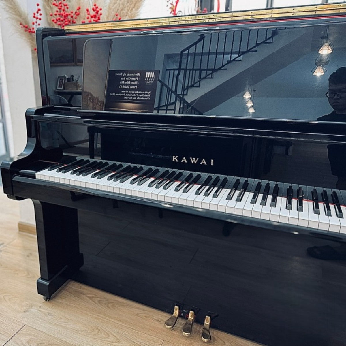 Đàn piano cơ Kawai US55 màu đen bóng sang trọng tại Tân Nhạc Cụ, thiết kế upright cao cấp với 3 pedal.