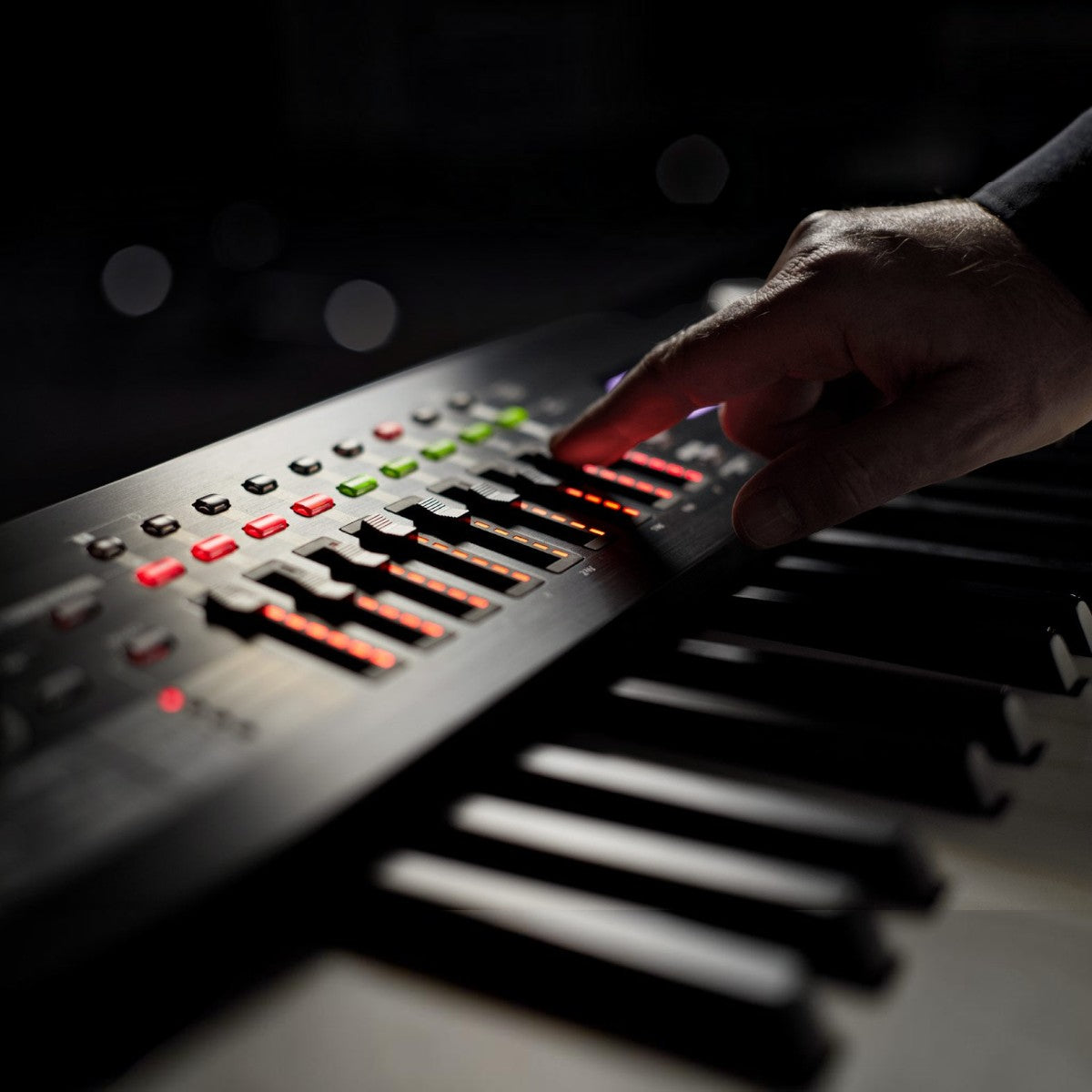 Tay nghệ sĩ điều chỉnh thanh trượt trên đàn piano điện Roland RD-2000 tại TÂN NHẠC CỤ với đèn LED rực rỡ
