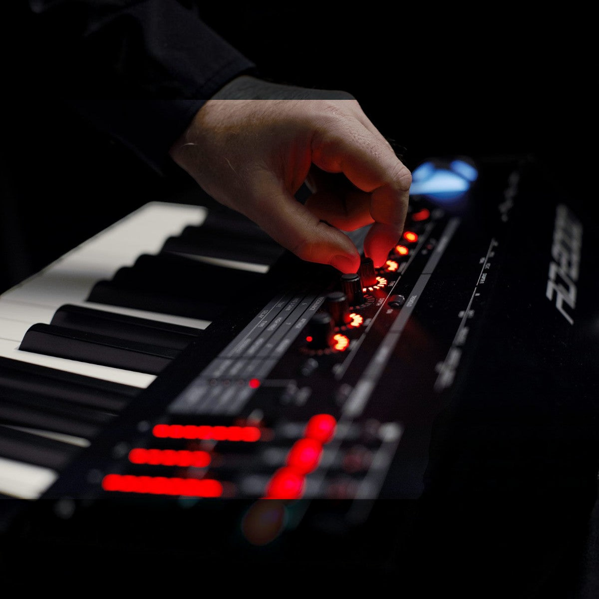 Nghệ sĩ đang điều chỉnh núm xoay trên đàn piano điện TÂN NHẠC CỤ Roland RD-2000 với đèn LED đỏ nổi bật