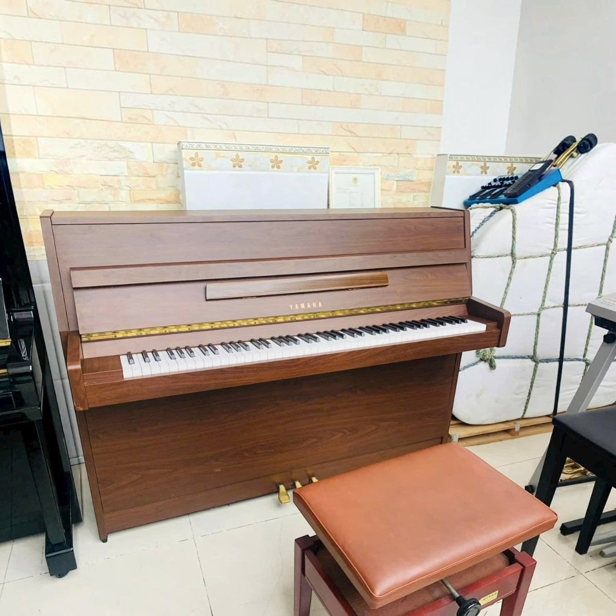 Đàn piano cơ TÂN NHẠC CỤ Yamaha MC101 vân gỗ Mahogany sang trọng, dáng console gọn nhẹ, màu nâu ấm áp.