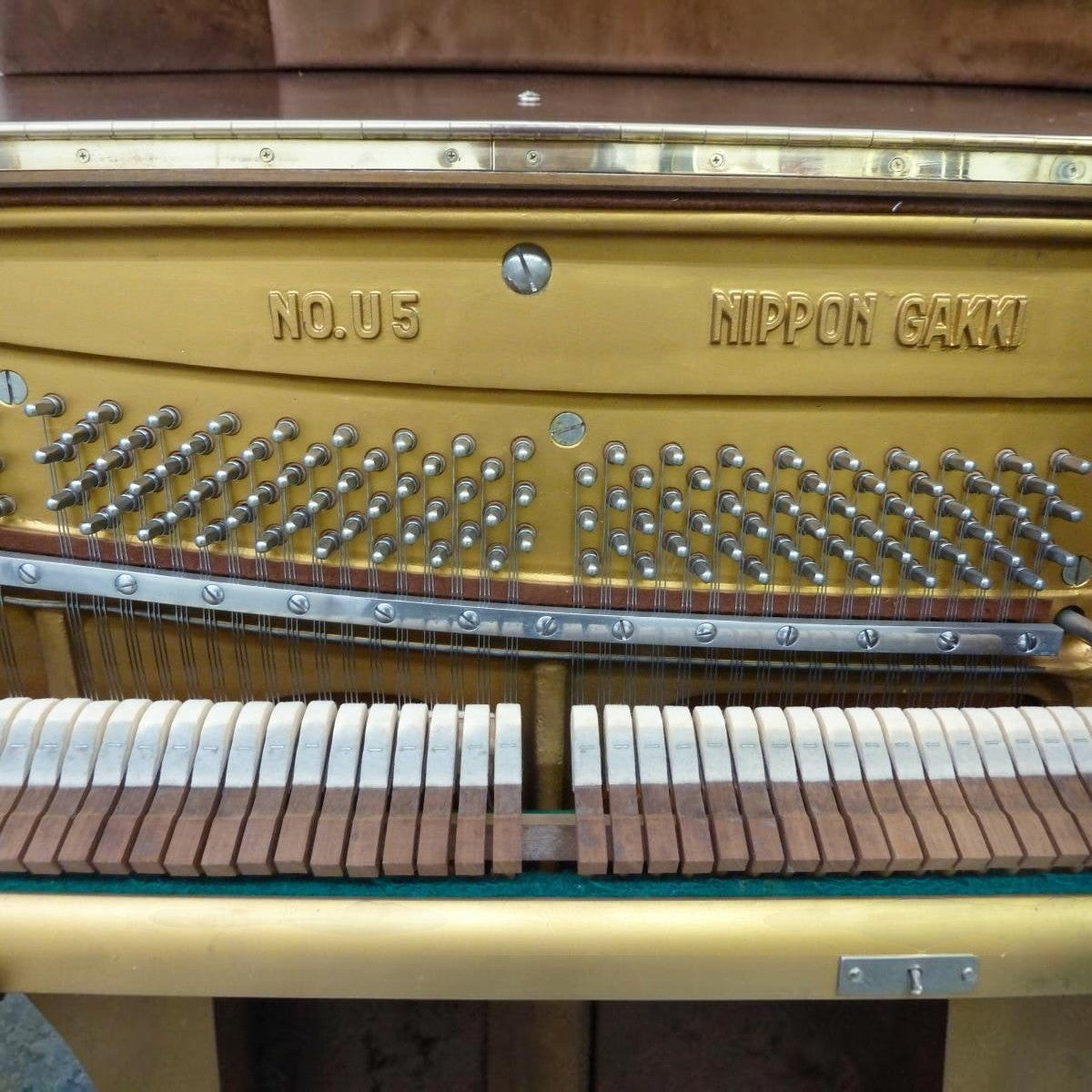 Khung gang vàng đồng bên trong đàn piano cơ Yamaha U5B tại Tân Nhạc Cụ với các chốt lên dây và búa đàn chi tiết
