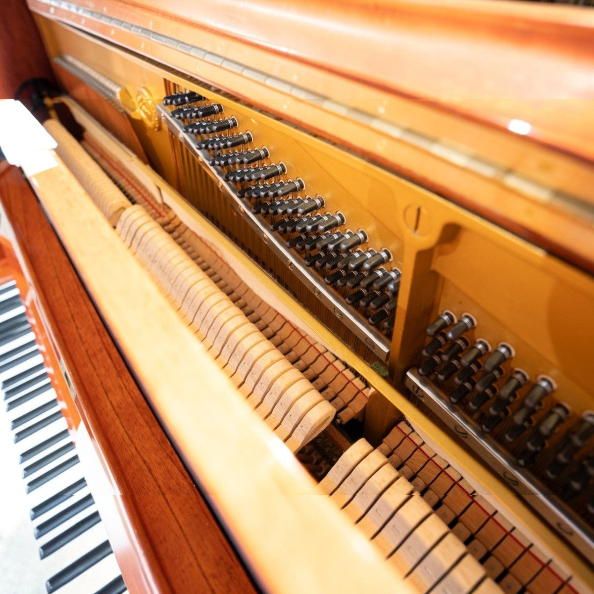 Cận cảnh bộ máy cơ bên trong đàn piano Yamaha W104 vân gỗ tại TÂN NHẠC CỤ với búa đàn và khung gang sắc nét