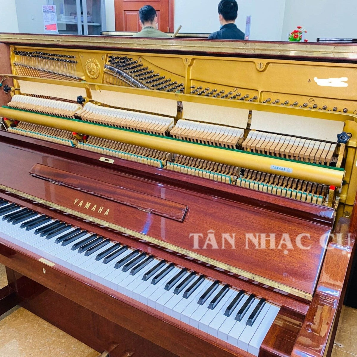 Đàn piano cơ Yamaha W106B tại TÂN NHẠC CỤ với mặt vân gỗ óc chó cổ điển, khung gang vàng và bộ máy bên trong chi tiết