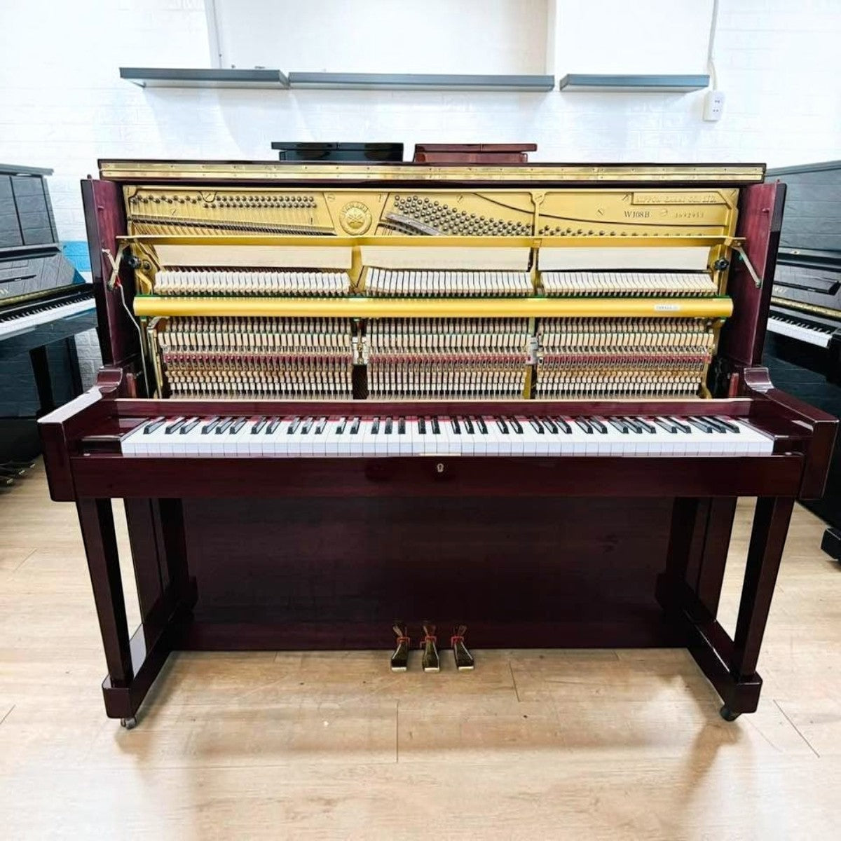 Đàn piano cơ Yamaha W108B cũ tại TÂN NHẠC CỤ với thiết kế vân gỗ nâu sẫm, lộ bộ máy bên trong và khung gang vàng